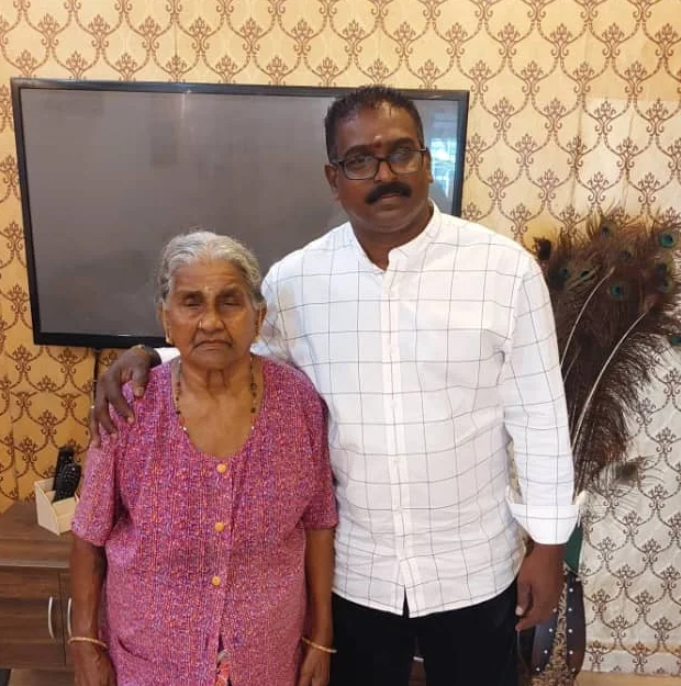 The coach with his mother at home, his arm around her shoulder.