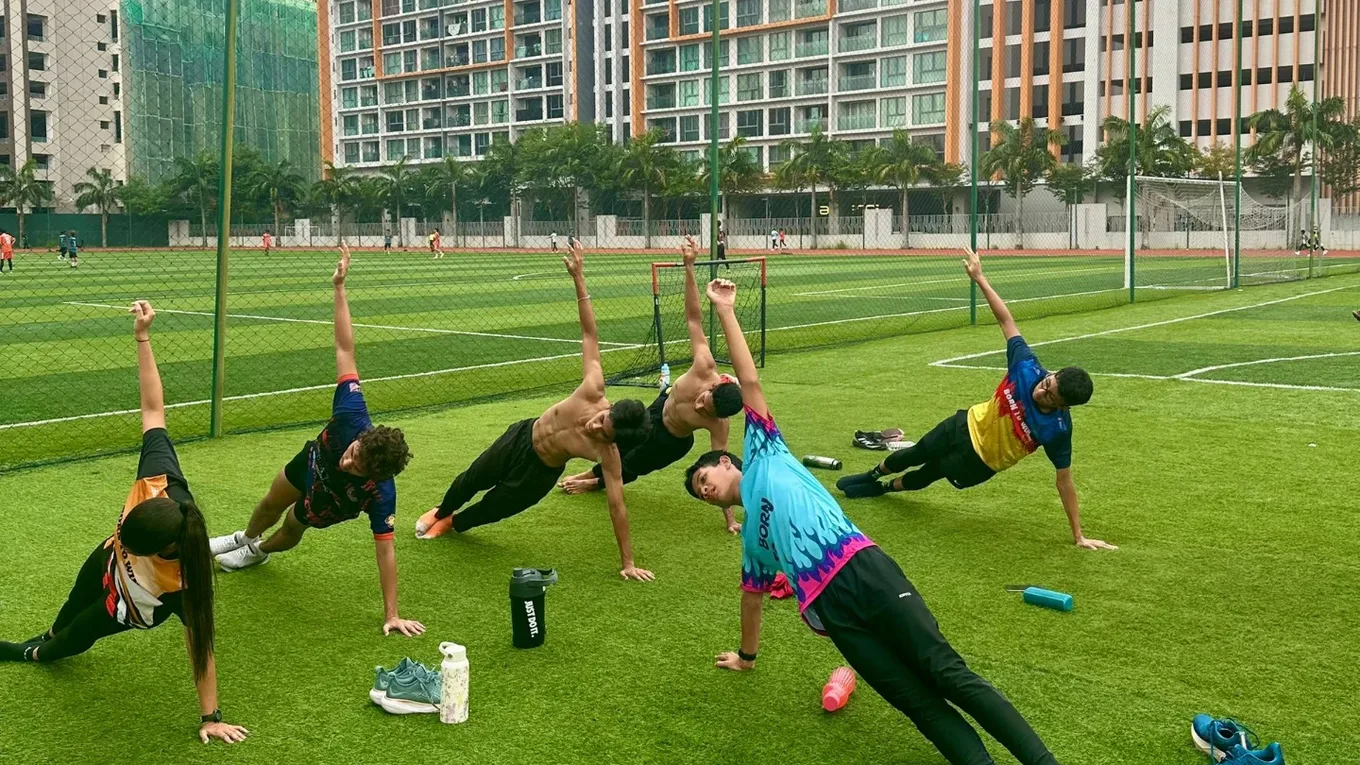The squad holding a side stretch in a line across the grass